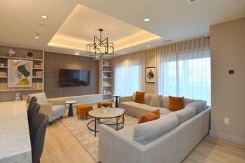 A modern living room with a large grey sofa, a black chair, a coffee table, and a television